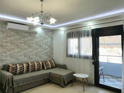 Una sala de estar con un sofá y una pared de ladrillos. en Iros Apartment, en Nea Peramos