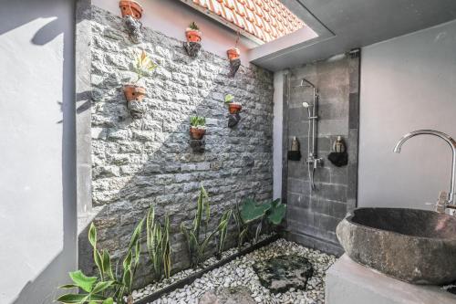 a bathroom with a stone wall and a sink at The Box Paradise Cottage in Nusa Penida