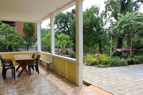 a porch with a table and chairs and a garden at Guest house Maspindzeli in Tskaltubo
