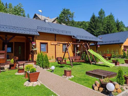 a log cabin with a playground in the yard at Drewniany Domek Daria i Tomek 2 domki na 8 osób in Stronie Śląskie