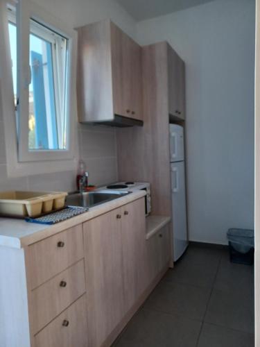 a kitchen with wooden cabinets and a sink and a window at Taxiarchis Studios in Áyios Yeóryios