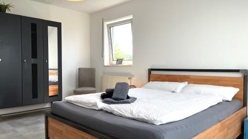 1 dormitorio con 1 cama con sombrero en favstay Industrialstyle 2-Zimmer 60qm mit Balkon, Panarbora Fernblick, 55" TV & Netflix, 55Mbit WLAN, Parkplatz, en Waldbröl