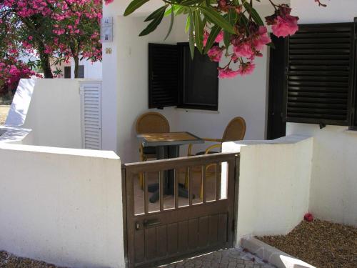 uma casa com um portão e uma mesa com flores cor-de-rosa em Retur Algarve Beach House em Castro Marim