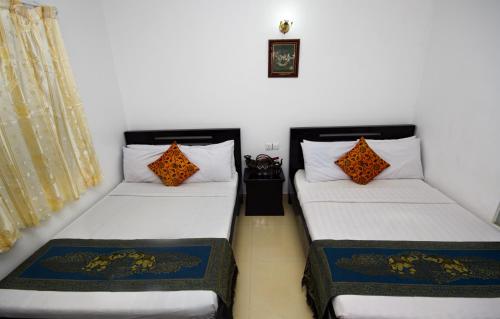 two beds in a room with white walls and orange pillows at King Boutique Hotel in Siem Reap