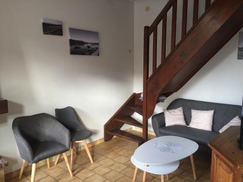a living room with a couch and chairs and a staircase at Maison au carrefour des terroirs in Pouançay