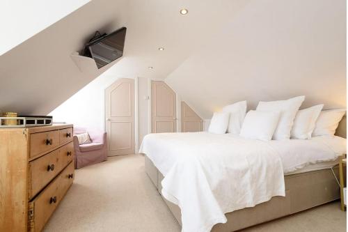 a white bedroom with a large bed with white pillows at Beautiful 3 bedroom cottage in the heart of Looe in Looe