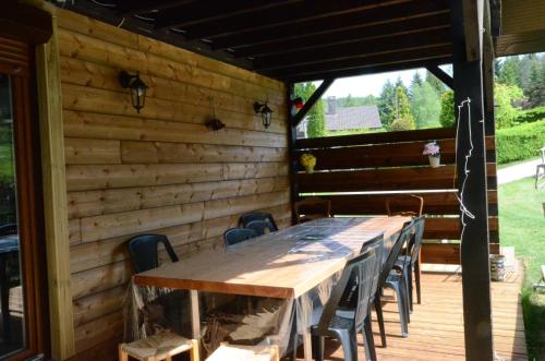 una larga mesa de madera y sillas en una terraza en le familial avec spa, sauna salle de jeux en Xonrupt-Longemer