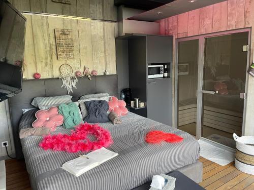 a bedroom with a bed with pink and green pillows at La chambre du puits avec 2 jacuzzis , sauna et Hammam privatif in Tournai
