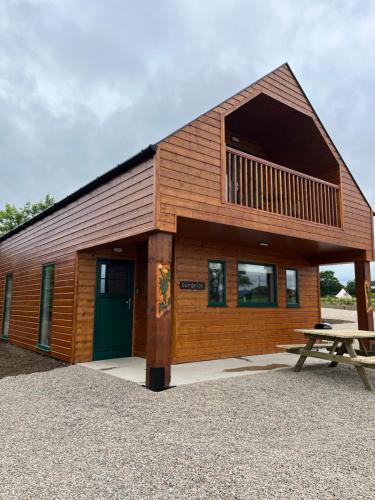 a cabin with a green door and a picnic table at Oakwell holiday village in Ramelton