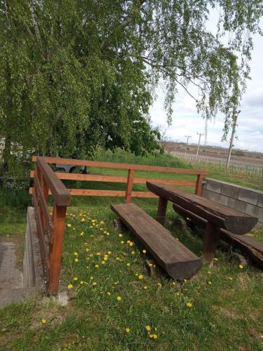 a wooden park bench sitting in the grass at Sklep U Petra in Velké Bílovice