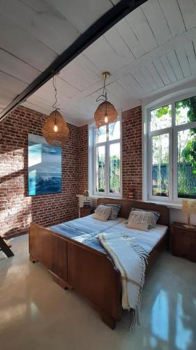 a bedroom with a large bed in a brick wall at Apartament Old School in Ustronie Morskie