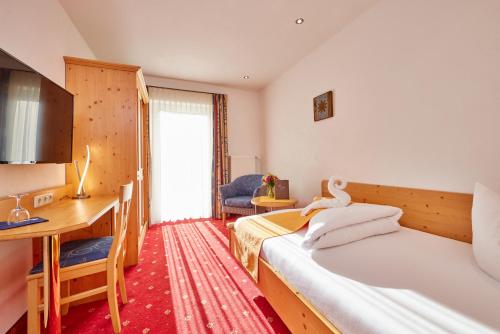 a hotel room with two beds and a desk at Alpenhotel Rieger in Mittenwald