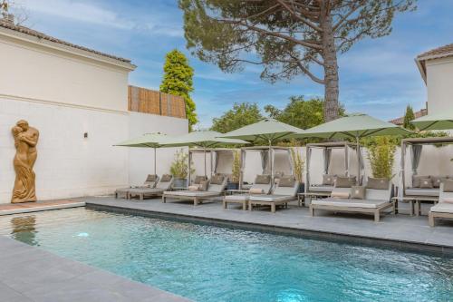 a swimming pool with lounge chairs and umbrellas at Le Saint Remy in Saint-Rémy-de-Provence