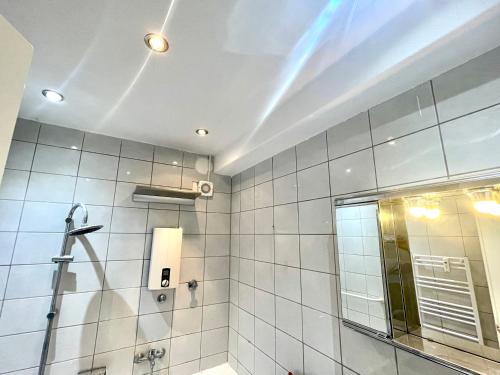 a white tiled bathroom with a shower and a mirror at Gracehomes in Herrenberg