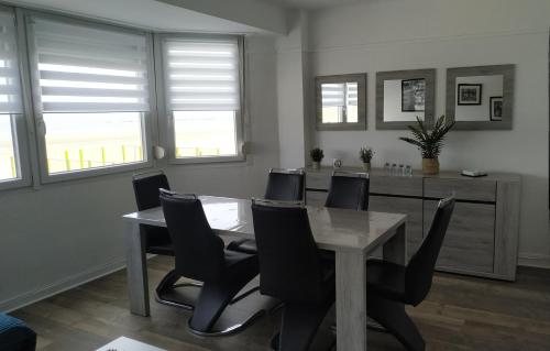 - une salle à manger avec une table, des chaises et des fenêtres dans l'établissement Magnifique Vue mer pour ce T2 totalement rénové classé meublé de tourisme 3 etoiles, à Dunkerque