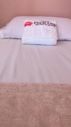 a white bed with a pillow with a flower on it at Pousada Flor de Lótus in São Félix do Tocantins
