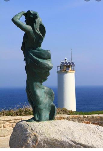 a statue of a woman with a lighthouse in the background at Vivienda 2 sin ascensor in Laxe