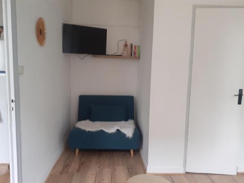 Cette chambre dispose d'une chaise bleue et d'une télévision. dans l'établissement Appart agréable, fonctionnel ! Proche commerces !, à La Bourboule