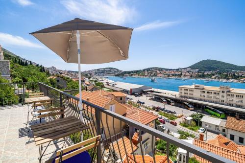 a balcony with an umbrella and a view of a city at Nostromo Guesthouse with the Sea View in Dubrovnik