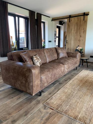 a brown leather couch in a living room at Vakantiewoning 't Rysselhof in Kaprijke