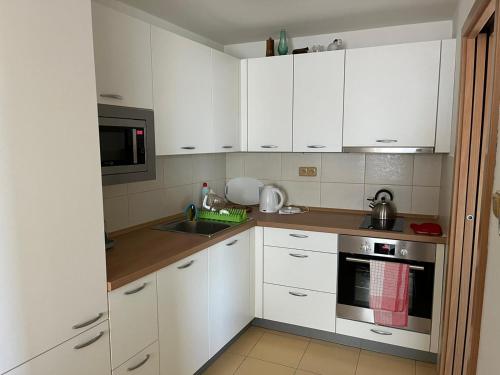 a kitchen with white cabinets and a sink at Apartmán Hotel Vomočil Bystré in Bystré