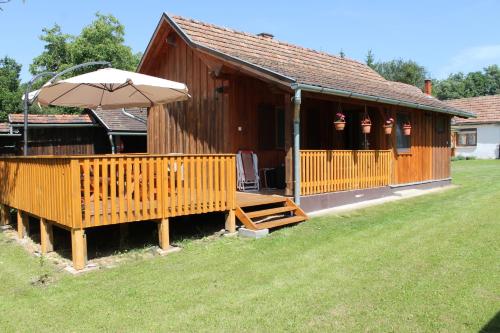 a wooden cabin with an umbrella and a yard at Orbán Porta in Szalafő