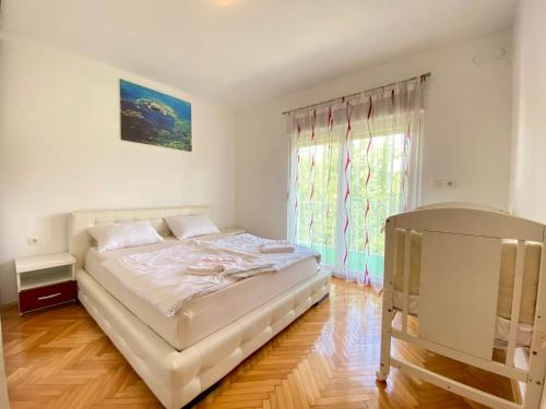 a white bedroom with a bed and a window at Guest House Ivano in Mostar