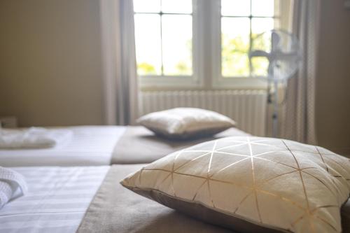 a bedroom with two beds with pillows and a window at MANOIR LE COUTUREAU maisons d'hôtes in Rouffignac-de-Sigoulès