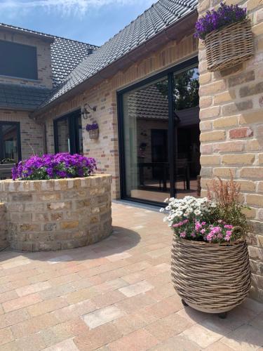a patio with two flower baskets and a building at Vakantiewoning 't Rysselhof in Kaprijke
