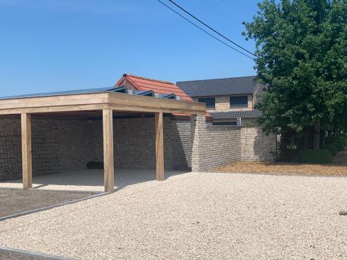 a garage with a wooden pavilion in front of a house at Vakantiewoning 't Rysselhof in Kaprijke