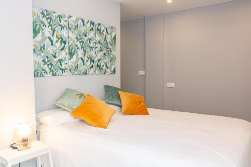 ein Schlafzimmer mit einem weißen Bett mit zwei orangefarbenen Kissen in der Unterkunft AP TURIST VELÁZQUEZ in Alicante