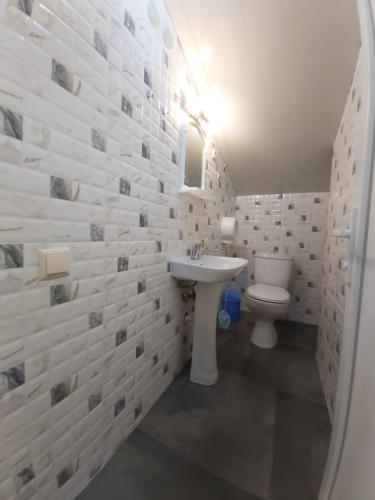 a white bathroom with a sink and a toilet at Hostel VOYAGE in Batumi