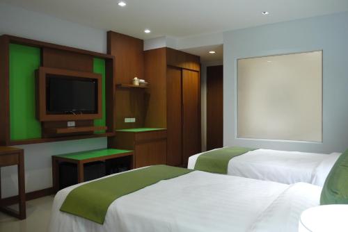 a hotel room with two beds and a flat screen tv at @Judy in Patong Beach