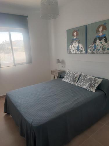 a bedroom with a blue bed with two pillows at Apartamento Punta Candor Rota in Cádiz