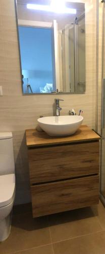 a bathroom with a sink and a toilet and a mirror at Apartamento Punta Candor Rota in Cádiz