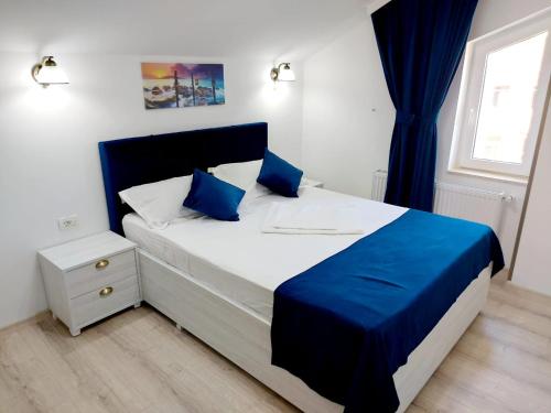 a bedroom with a large bed with blue pillows at Vila Coty in Mamaia Nord