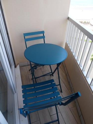 Una mesa azul y dos sillas en un balcón. en Studio alcôve, vue mer, 4 personnes, Saint Jean de Monts, en Saint-Jean-de-Monts