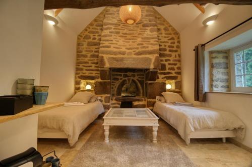 two beds in a room with a stone fireplace at KERBELEG, ferme-manoir du XVè siècle, chambres grand confort in Riec-sur-Bélon