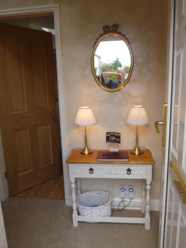a room with a table with two lamps and a mirror at Garden Suite in Rhuddlan