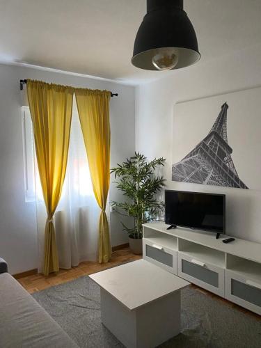 ein Wohnzimmer mit einem TV und gelben Vorhängen in der Unterkunft Tranquilo piso en Cimadevilla in Gijón