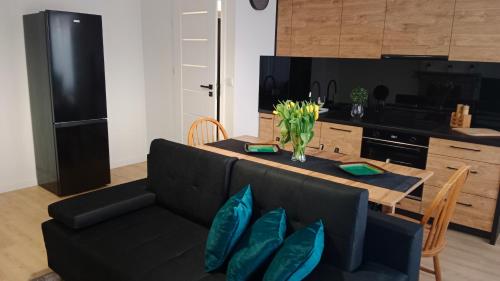 a living room with a black couch and a table at APARTAMENT DWUPOKOJOWY in Ostrowiec Świętokrzyski