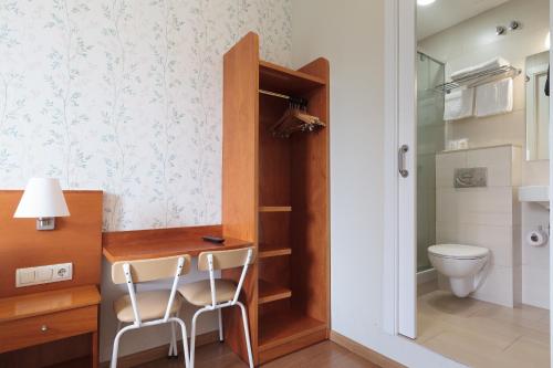 a bathroom with a toilet and a desk with two chairs at Hostal Oliva in Barcelona