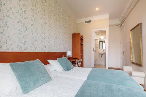 a bedroom with a large white bed with blue pillows at Hostal Oliva in Barcelona