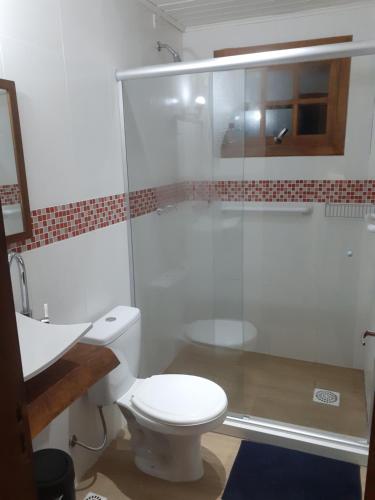 uma casa de banho com um WC e uma cabina de duche em vidro. em Paraíso dos Ciclistas em Gramado