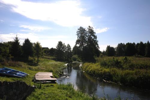 a river with a bridge and boats in a field at Bojarski Gościniec in Narewka