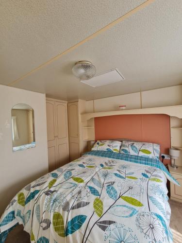 een slaapkamer met een bed met een kleurrijke sprei bij Hemsby Caravan Hire in Hemsby