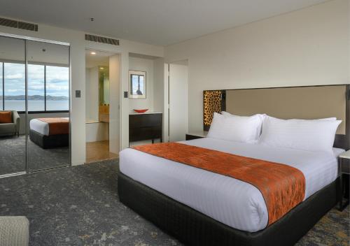 a hotel room with a bed, chair, and nightstand at Hotel Grand Chancellor Hobart in Hobart