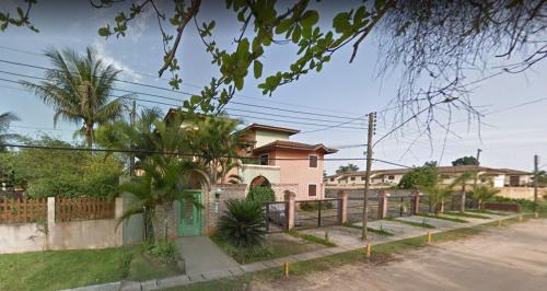 a pink house with a fence in front of it at Apartamento Duplex a 100 metros da Praia de Boracéia in Bertioga