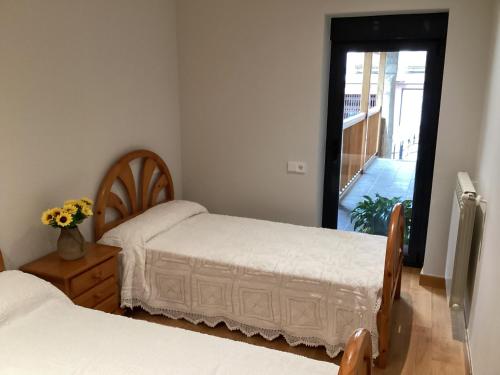 1 dormitorio con 2 camas y puerta a un balcón en Casa do Corredor, en Chantada