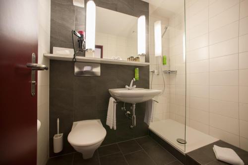 La salle de bains est pourvue de toilettes, d'un lavabo et d'une douche. dans l'établissement Weisses Kreuz, à Lyss